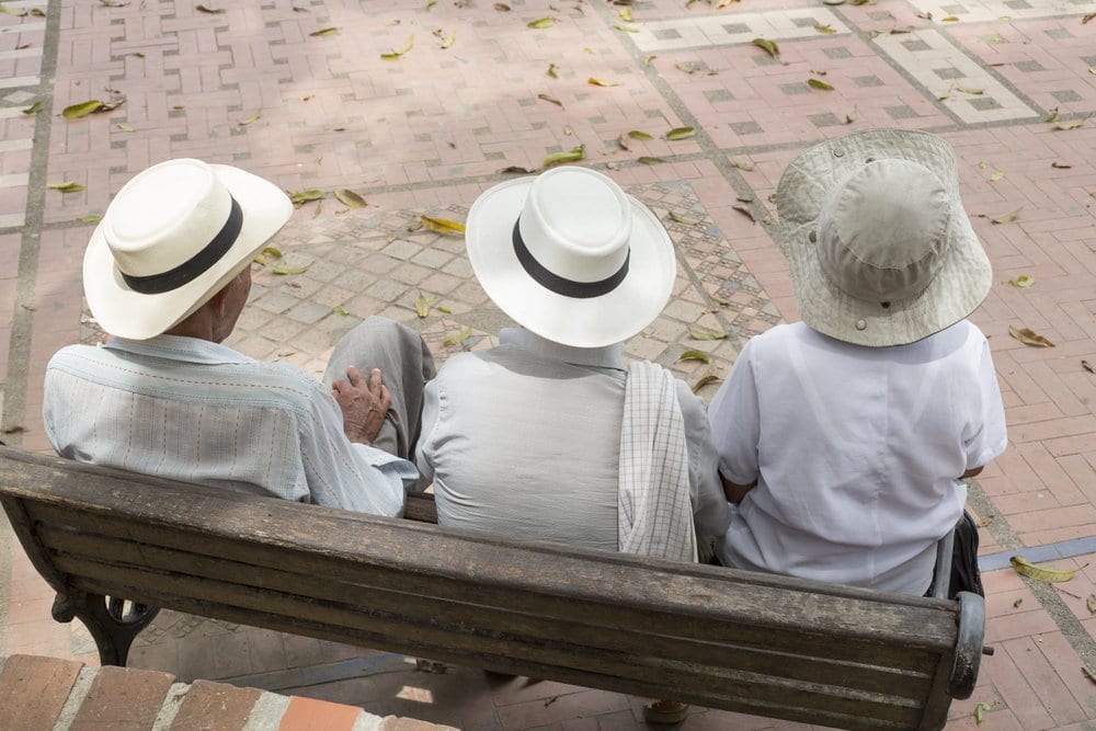 Three people with hat resting on bench